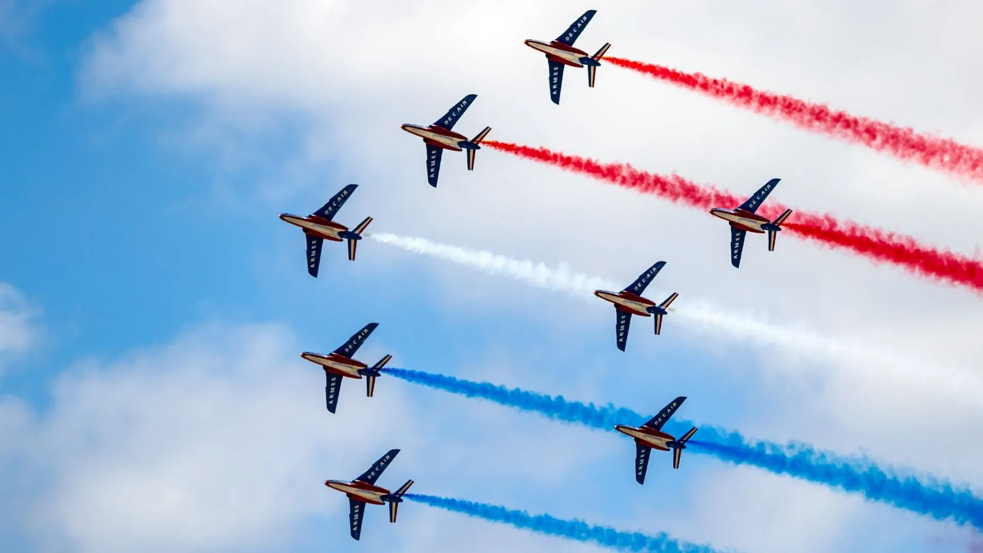 Patrouille de France en formation diamant avec neuf Alphajet de l'armée de l'air libérant des fumées tricolores bleu blanc rouge dans le ciel