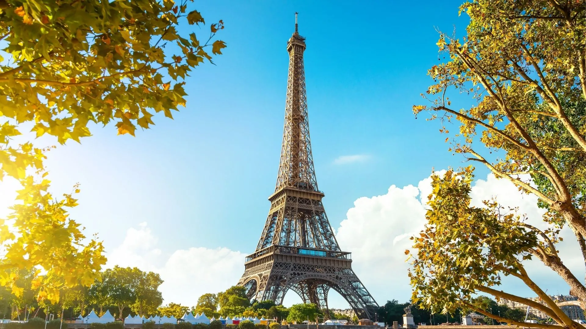 Tour Eiffel à Paris en automne, monument emblématique français de 330 mètres construit par Gustave Eiffel en 1889, vue depuis le Champ-de-Mars avec feuillages dorés
